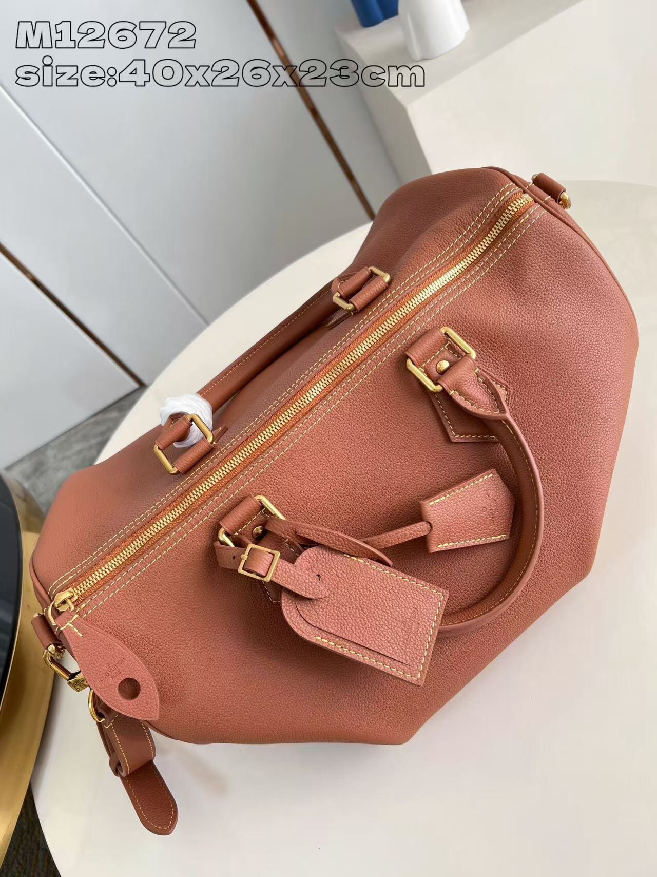 P2100 M12672 Marrón Este lujoso bolso Speedy Bandoulière 40 está confeccionado en piel de ternero ultrasuave y cuenta con un rico forro de piel de cordero de color coñac Incluye una bolsa de piel desmontable Dos asas superiores enrolladas de piel y una correa para el hombro desmontable y ajustable Para unas opciones de transporte versátiles Tamaño: 40x26x23cm