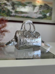 P1360 Lv M11987 SPEEDY BANDOULIÈRE 20 HANDBAG silver patent leatherThis Speedy Bandoulière 20 bag from the LV Ski collection is made of embossed coated canvas embellished with smooth leather trimmings and shiny metal pieces, and features a new Monclerogram Miroir effect for a retro-futuristic look. The detachable and adjustable leather shoulder strap allows for a variety of carrying options, and the compact design allows for storing a long wallet and other daily essentials. 12 x 20.5 cm