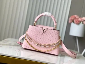 LV Pink Ostrich Pearl Trilogy Chain Clause 🔸Esta bolsa Capucines adiciona o clássico couro de vaca Taurillon à coleção Trilogy, dando à elegante corrente uma textura semelhante a uma concha que pode ser usada para iluminar um visual noturno. O compartimento interior inclui um bolso para cartões que é adequado para uso transversal ou portátil.