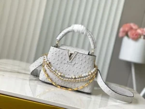 LV Grey Ostrich Pearl Trilogy Chain Clause 🔸Esta bolsa Capucines acrescenta a clássica pele de vaca Taurillon à coleção Trilogy, conferindo à elegante corrente uma textura semelhante a uma concha que pode ser usada para alegrar um look noturno. O compartimento interior inclui um bolso para cartões que pode ser usado ao longo do corpo ou numa posição de mão.