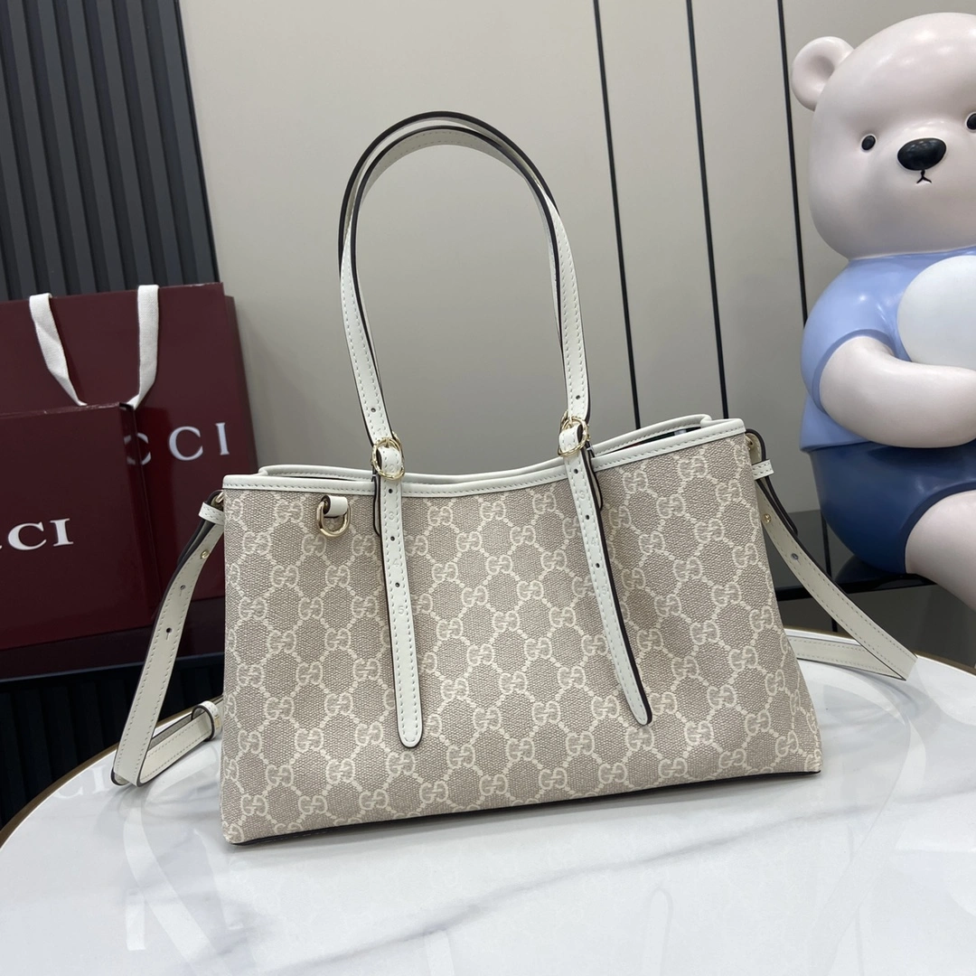 p960 Gucci Emblem系列焕新诠释品牌的隽永优雅风范和精湛工艺这款小号托特包配有可调节手柄饰以示数孔眼灵感源自马术世界米色和白色全新GG字母图案涂层织物米白色皮革滚边饰对比色缝线另配有用于系挂可拆卸物品的D形环饰示数孔眼可调节手柄；高18厘米 – 28厘米内部：2个隔层和1个中央拉链隔层可调节皮革肩带（高51.5厘米 – 57厘米）；长度可在104厘米与114厘米之间调节磁力按扣开合型号：815214尺寸：30厘米（宽）x 18厘米（高）x 11厘米（深）颜色：米胶白皮/重量：约0.8千克意大利创作-高仿包包