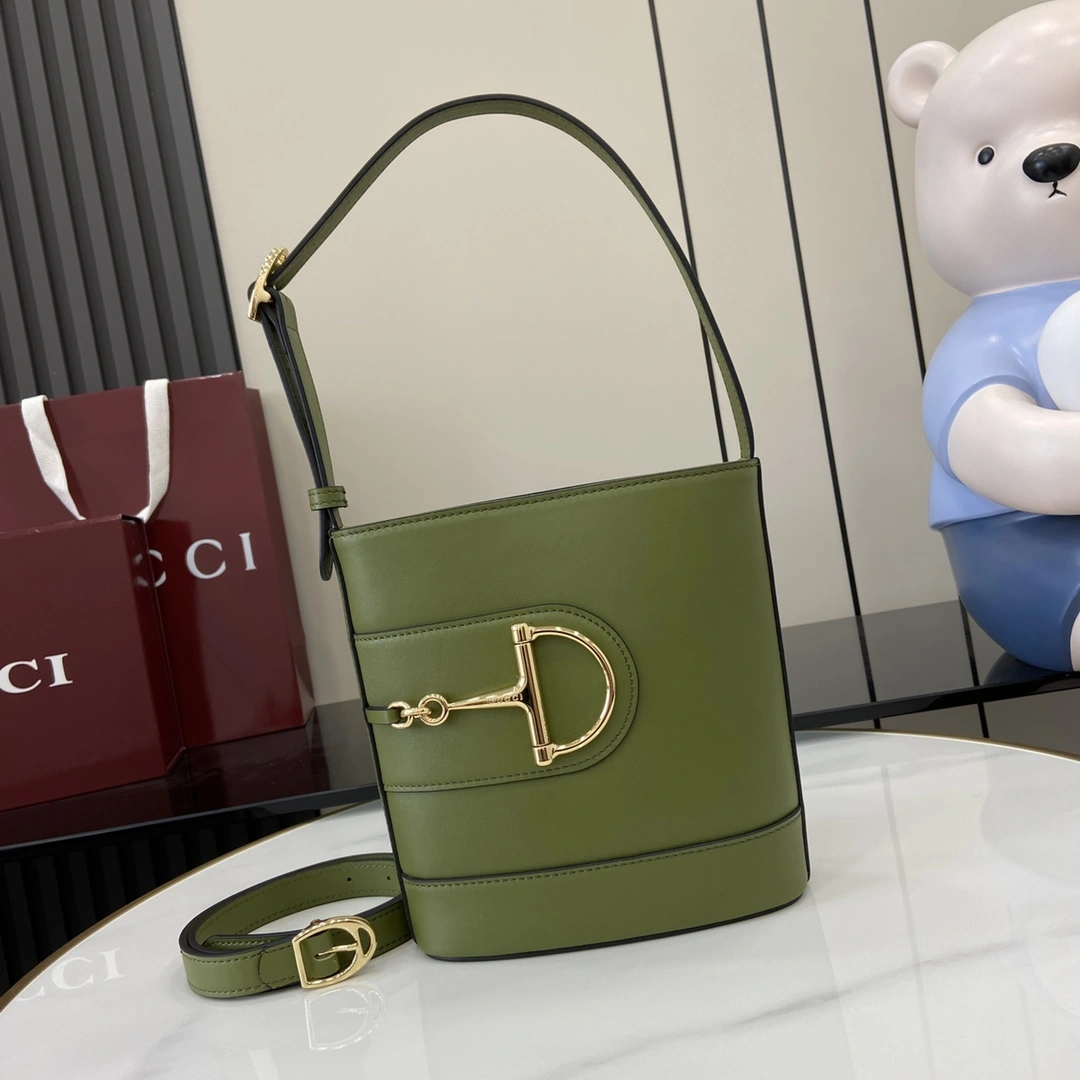 p1080 Para la colección Primavera/Verano 2025 Gucci 73 se inspira en un bolso cubo de colección lanzado el mismo año que el homónimo de la colección Este bolso es una interpretación estética moderna del accesorio con forma de bocado que puede llevarse cruzado, colgado del hombro o como bolso tote Piel brillante verde Tono dorado Accesorio de gran tamaño con forma de medio bocado Forro en mezcla de algodón y lino marrón Interior: 1 bolsillo con cremallera Correa para el hombro (19 cm de altura); Cierre con hebilla magnética Modelo: 833665 Medidas: 18,5 cm (ancho) x 20 cm (alto) x 8,5 cm (fondo) Color: Verde Piel/peso: aprox. 0,5 kg Creaciones italianas-Bolsos de alta imitación