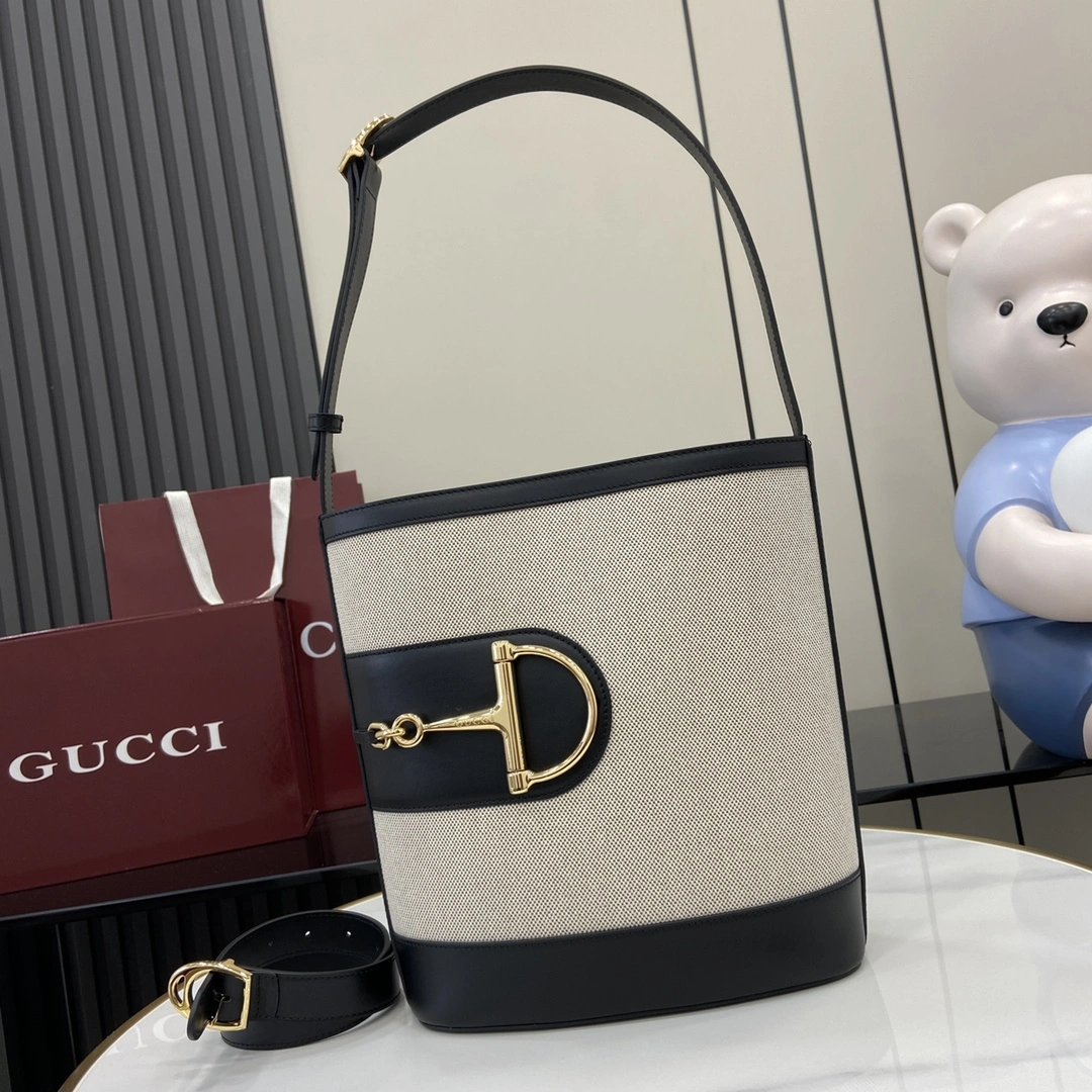 p1160 在2025春夏系列中Gucci 73的灵感来源于同名年份的档案桶包它采用了当代的马蹄扣硬件设计可以斜挎、单肩背或作为手提包使用天然帆布黑色皮革装饰金色调大号半马刺五金件棕色棉麻衬里内部：1个拉链口袋肩带（27厘米高）附赠可拆卸包带（50厘米高）磁扣开合型号：833660尺寸：26厘米（宽）x27.5厘米（高）x11.5厘米（深）颜色：白布黑皮/重量：约0.8千克意大利创作-高仿包包