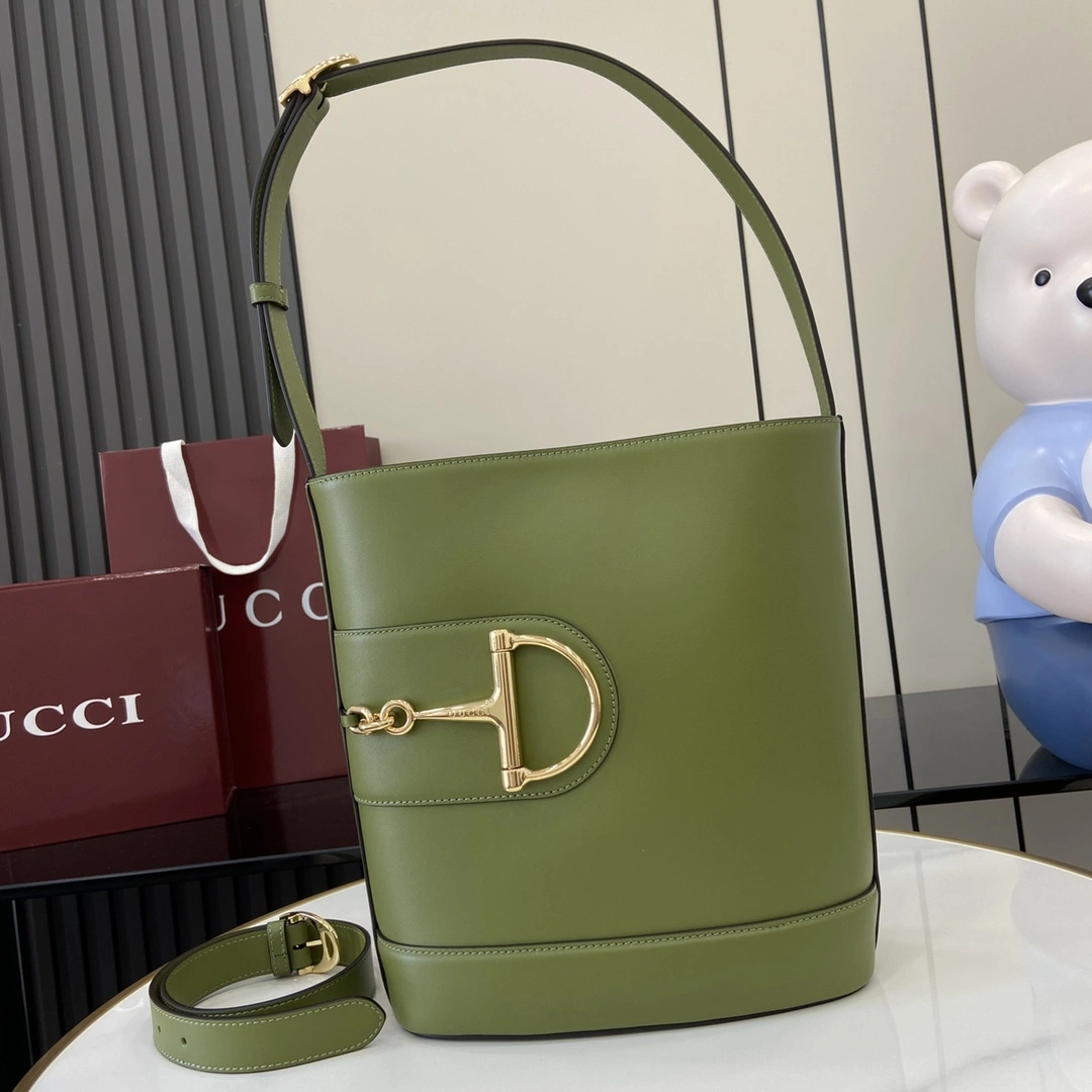 p1380 For the Spring/Summer 2025 collection Gucci 73 takes inspiration from a collectible bucket bag launched in the same year as its namesake This bag is a modern aesthetic interpretation of the horsebit shape accessory can be worn crossbody, over the shoulder or as a handbagGreen glossy leatherGold tonesOversized half horsebit shape accessoryBrown cotton and linen blend liningInterior: 1 x zipper pouchShoulder strap (27 cm high); Comes with detachable bag (50 cm high) Magnetic snap closure Model: 833660 Size: 26 cm (W) x 27.5 cm (H) x 11.5 cm (D) Color: Green Full Leather/Weight: Approx. 0.8 kg Italian Creations-High-Fashion Bags